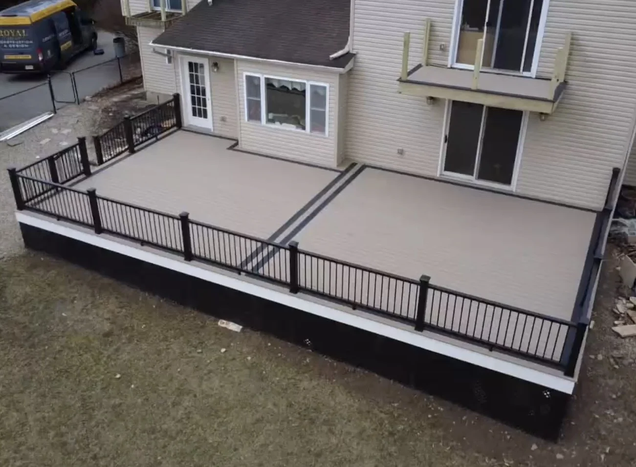 An elevated view of a completed deck with contrasting borders and black railings.