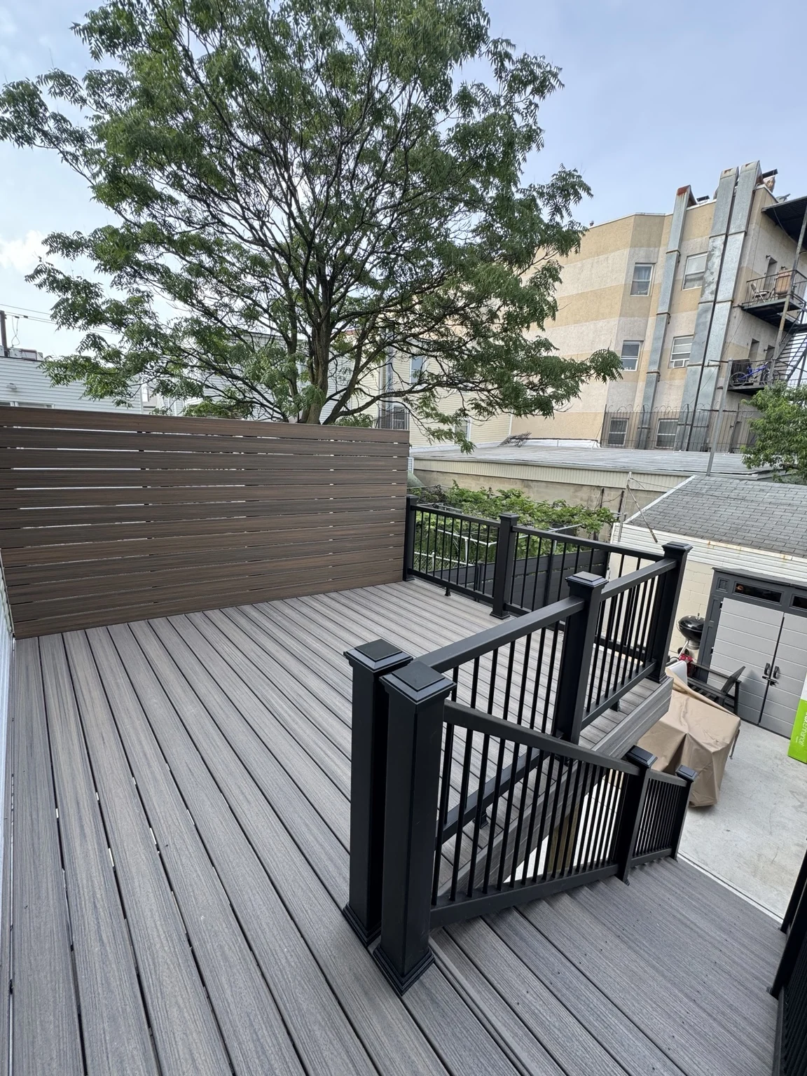 A raised grey deck with black railings and a horizontal privacy wall.