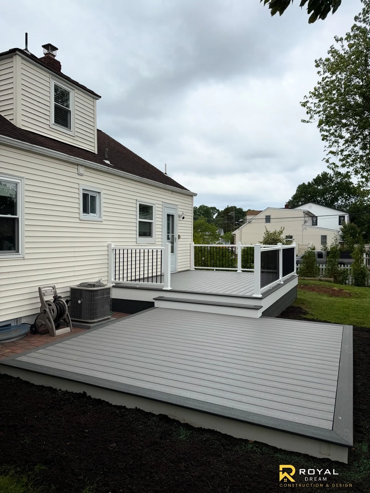 Grey decking connects a broad lower platform with an upper deck framed by white posts and black balusters.