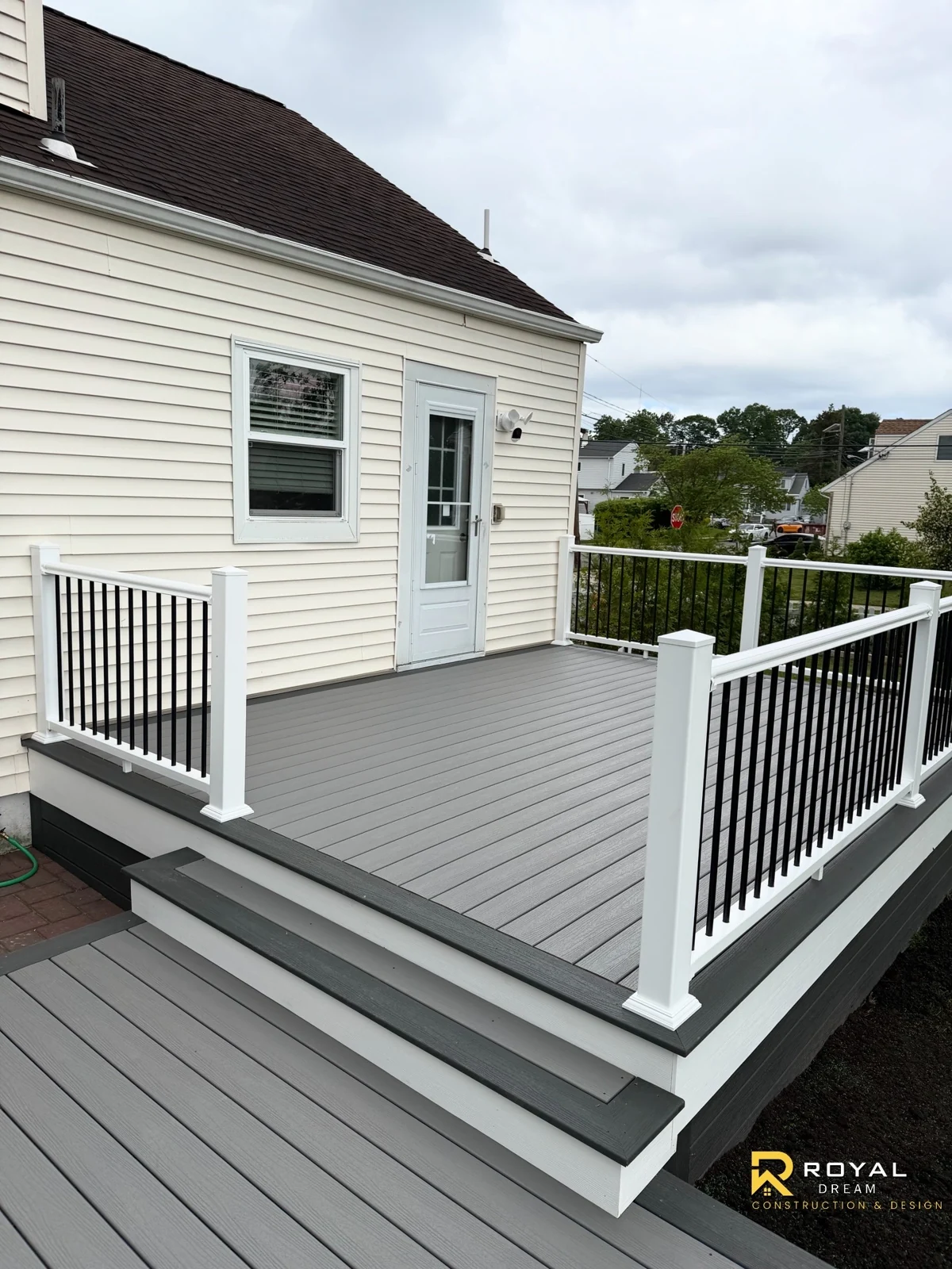 Grey deck boards, wide steps and white railings with black balusters create a welcoming outdoor space.