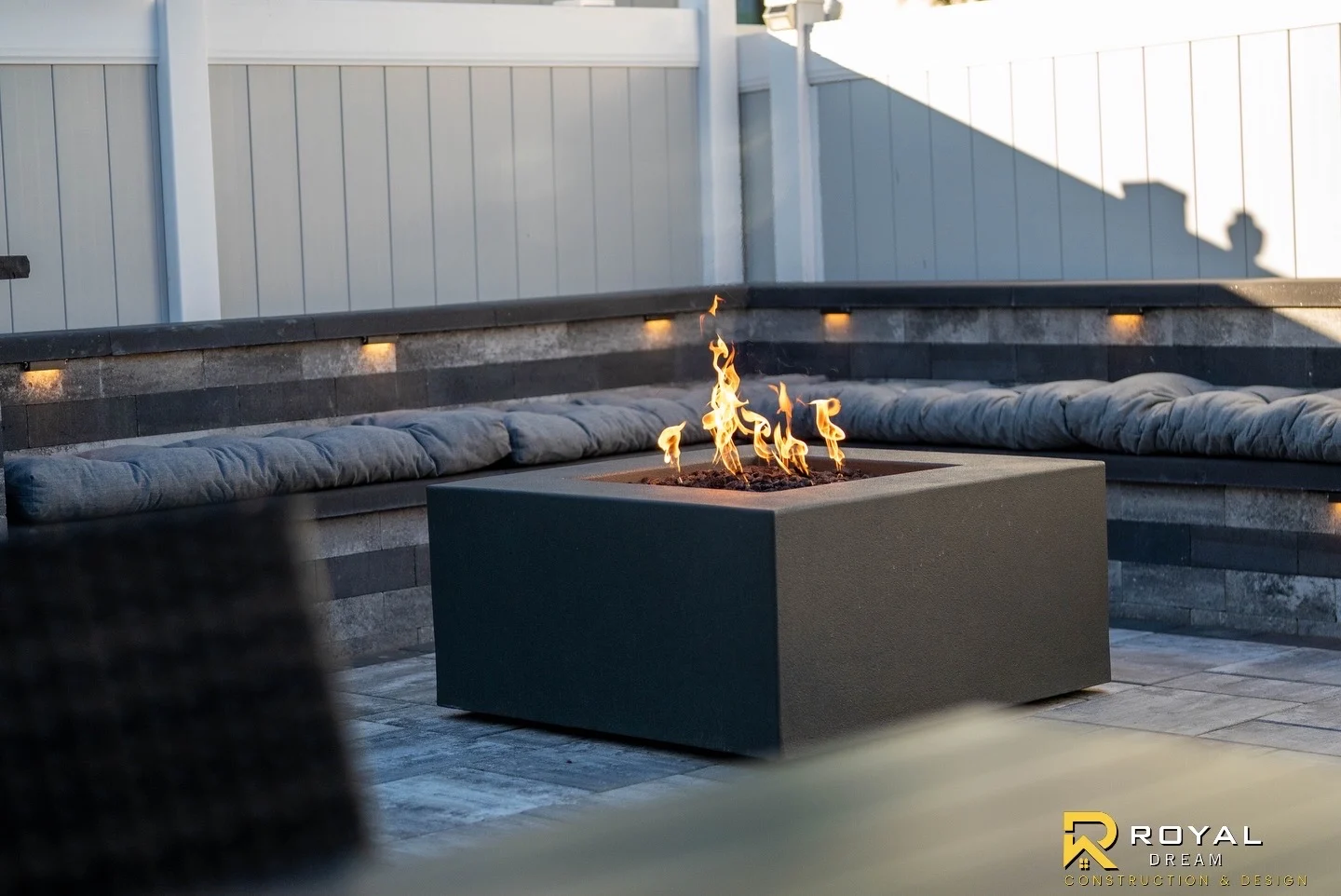 A fire feature sits within a masonry seating area with integrated lighting.