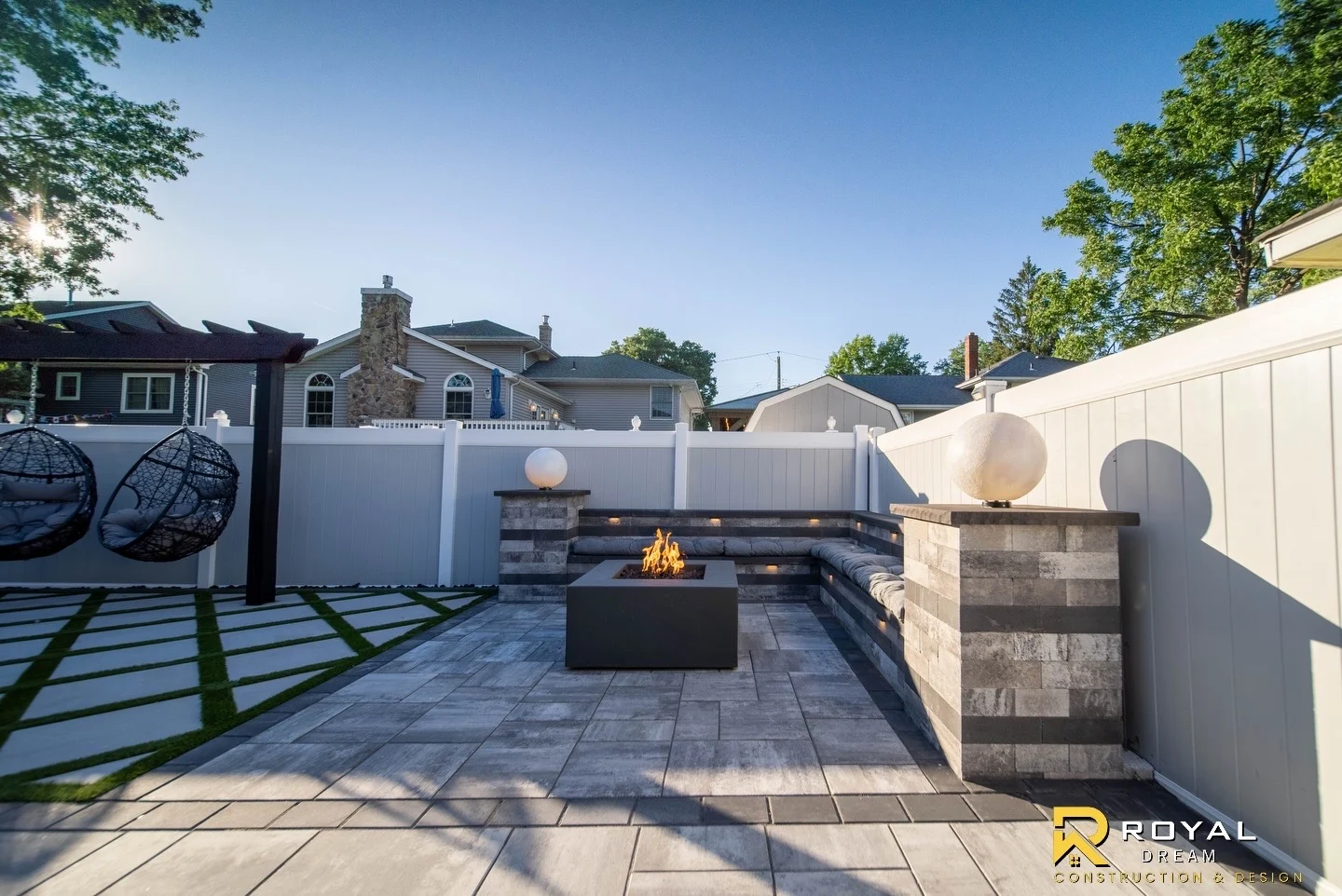 A paved lounge with built-in seating, a fire feature and decorative water spheres.