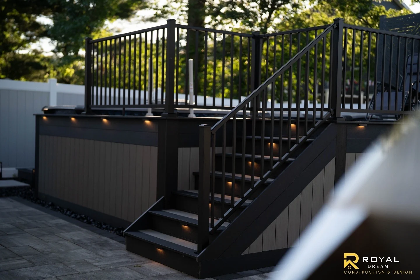 Dark railings, contrasting deck skirting and stair lighting complete the adjoining deck.